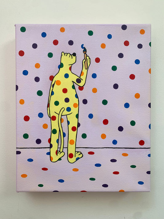 Canvas painting on a white wall of the yellow leopard covered in rainbow spots standings with his back facing us. He has a paintbrush in hand and is painting the spots on the wall.