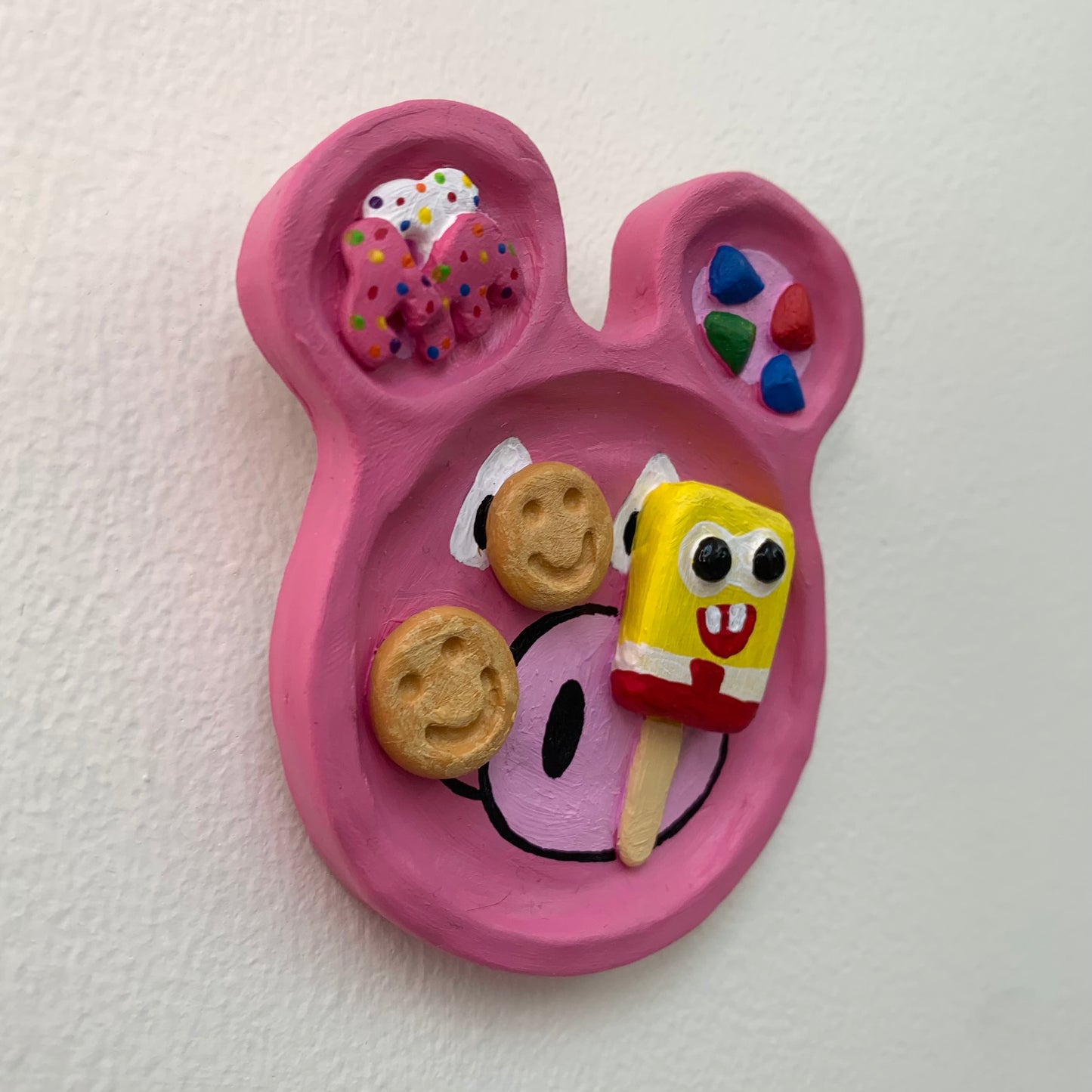 Pink character-shaped plate with cookies and a popsicle on a white background