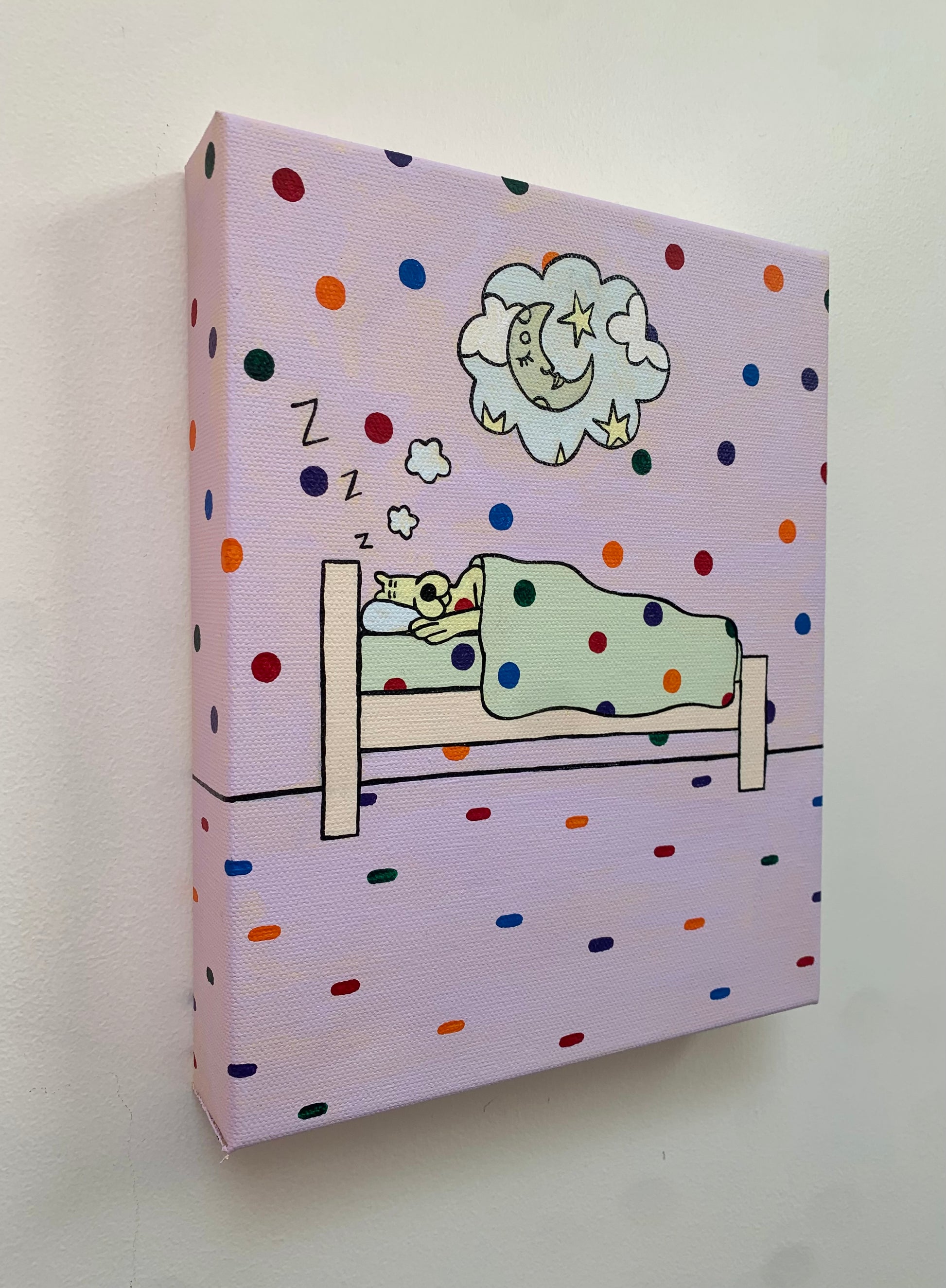 Canvas painting against a white wall of a sleeping yellow leopard under a blanket. Side view of the bed. Dream clouds with an image of a moon a stars. Rainbow spots all over the background.