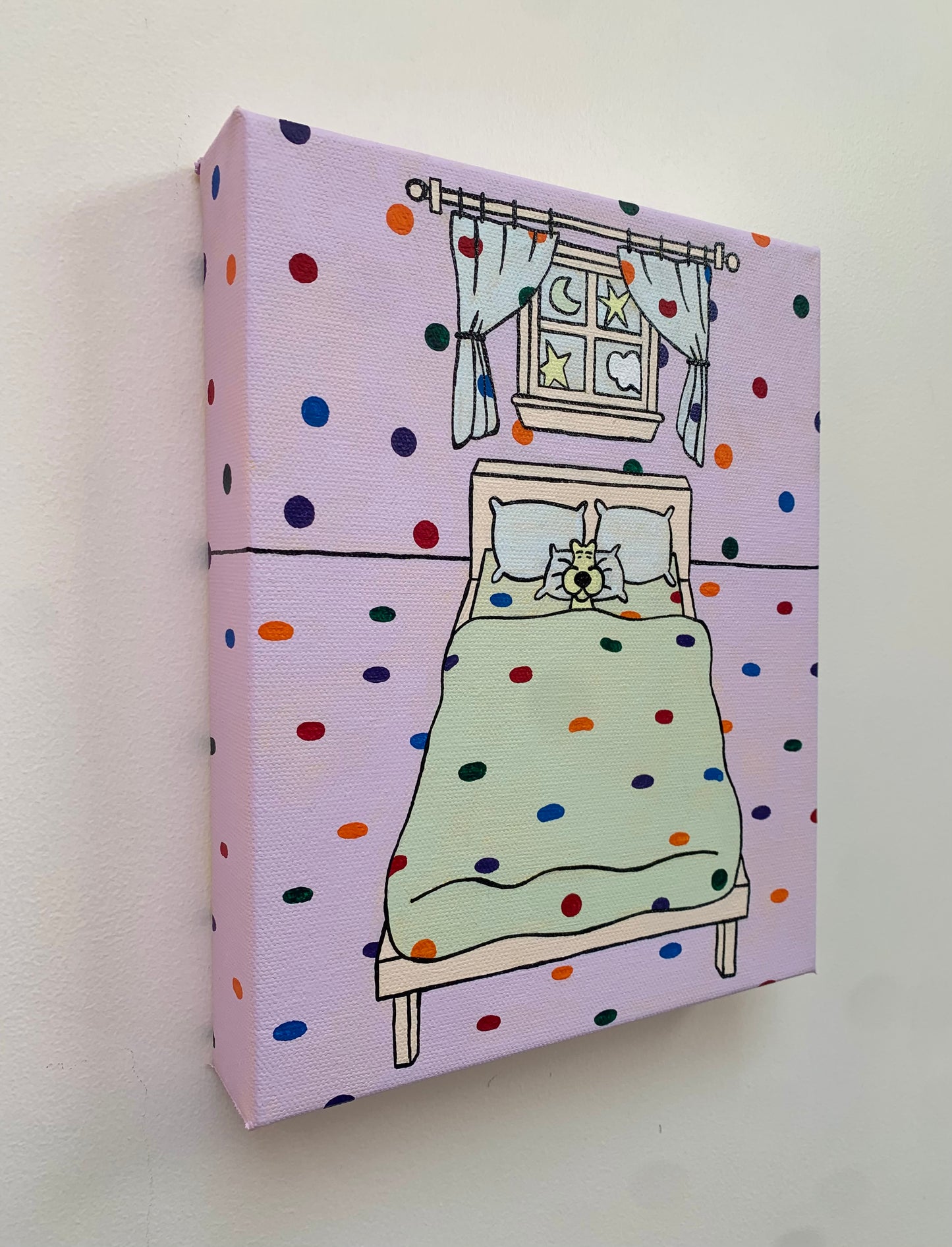 Canvas painting on a white wall of a cartoon bedroom with rainbow polka dot walls, bed, and window with curtains and a moon outside. Sleeping leopard in the bed. 