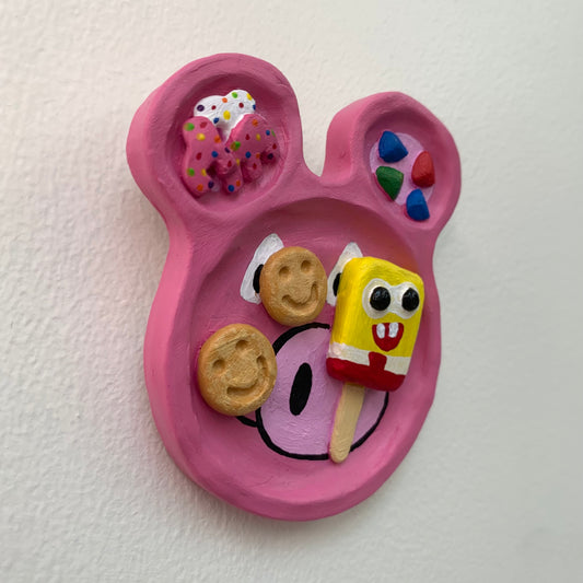Pink character-shaped plate with cookies and a popsicle on a white background