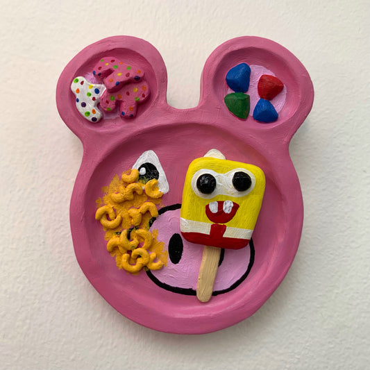 Pink plate with cartoon character design and colorful food on a white background
