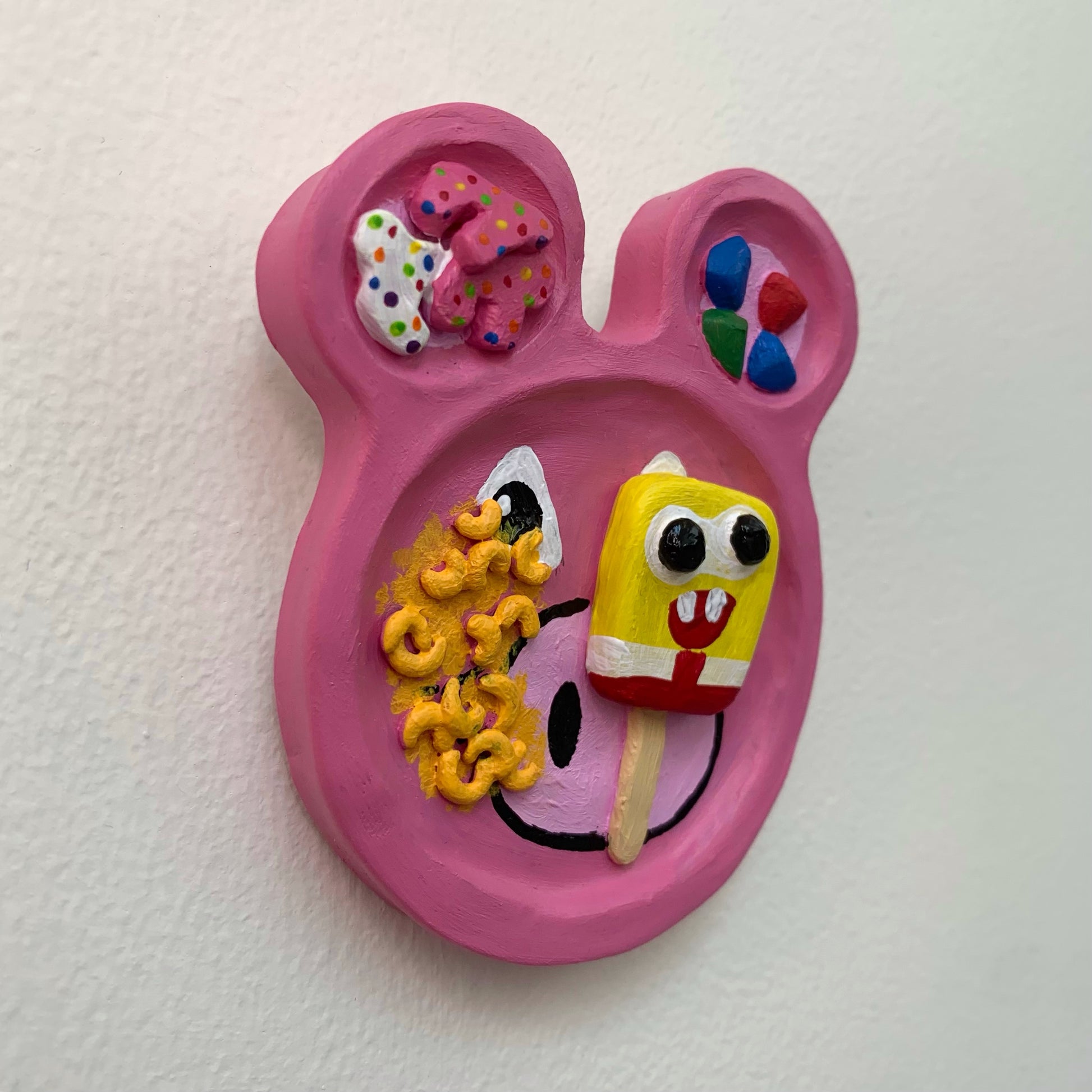 Pink character-shaped plate with colorful food on a white background