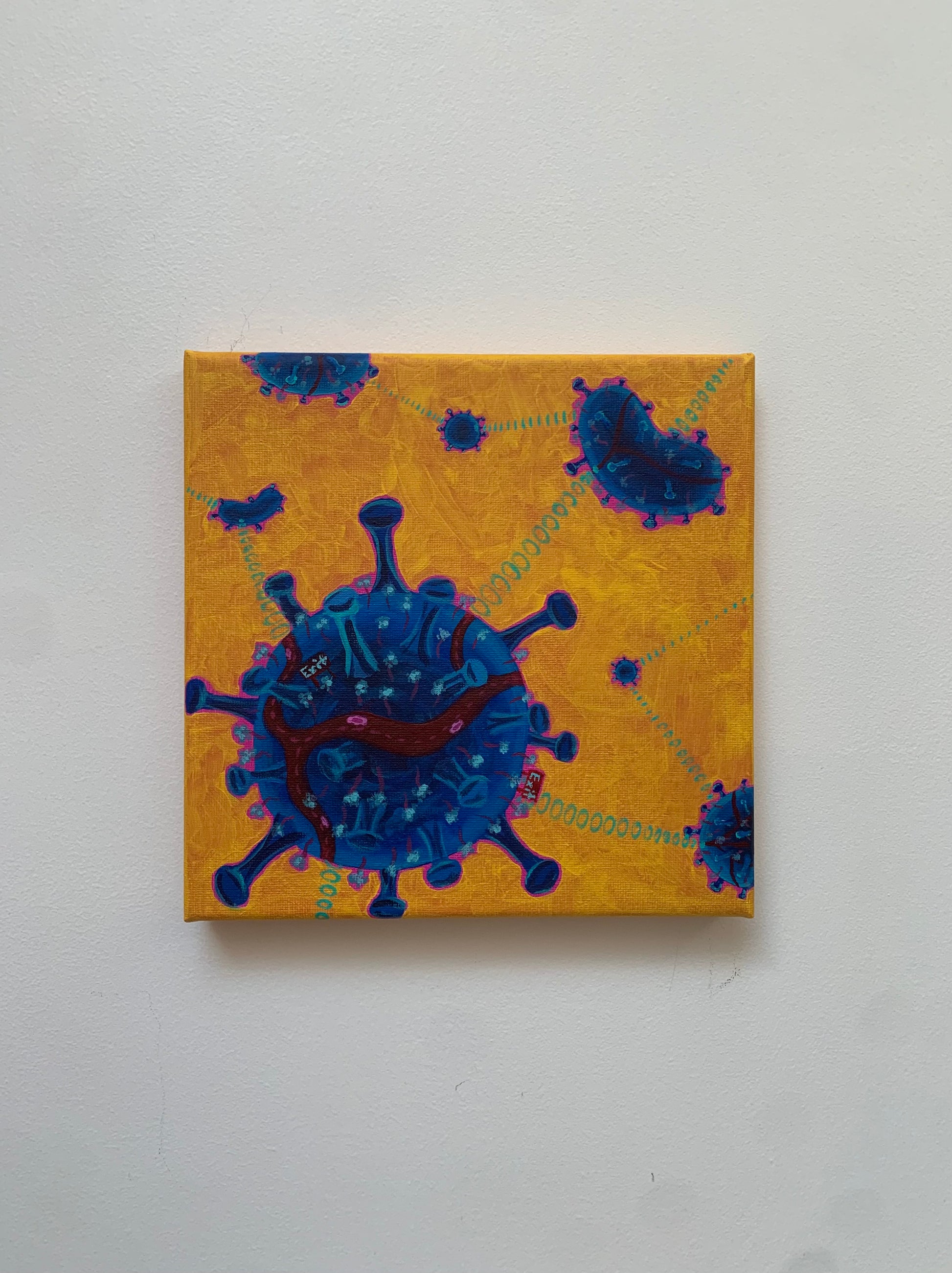 Canvas print of a blue virus-like shape on a yellow background with green text.