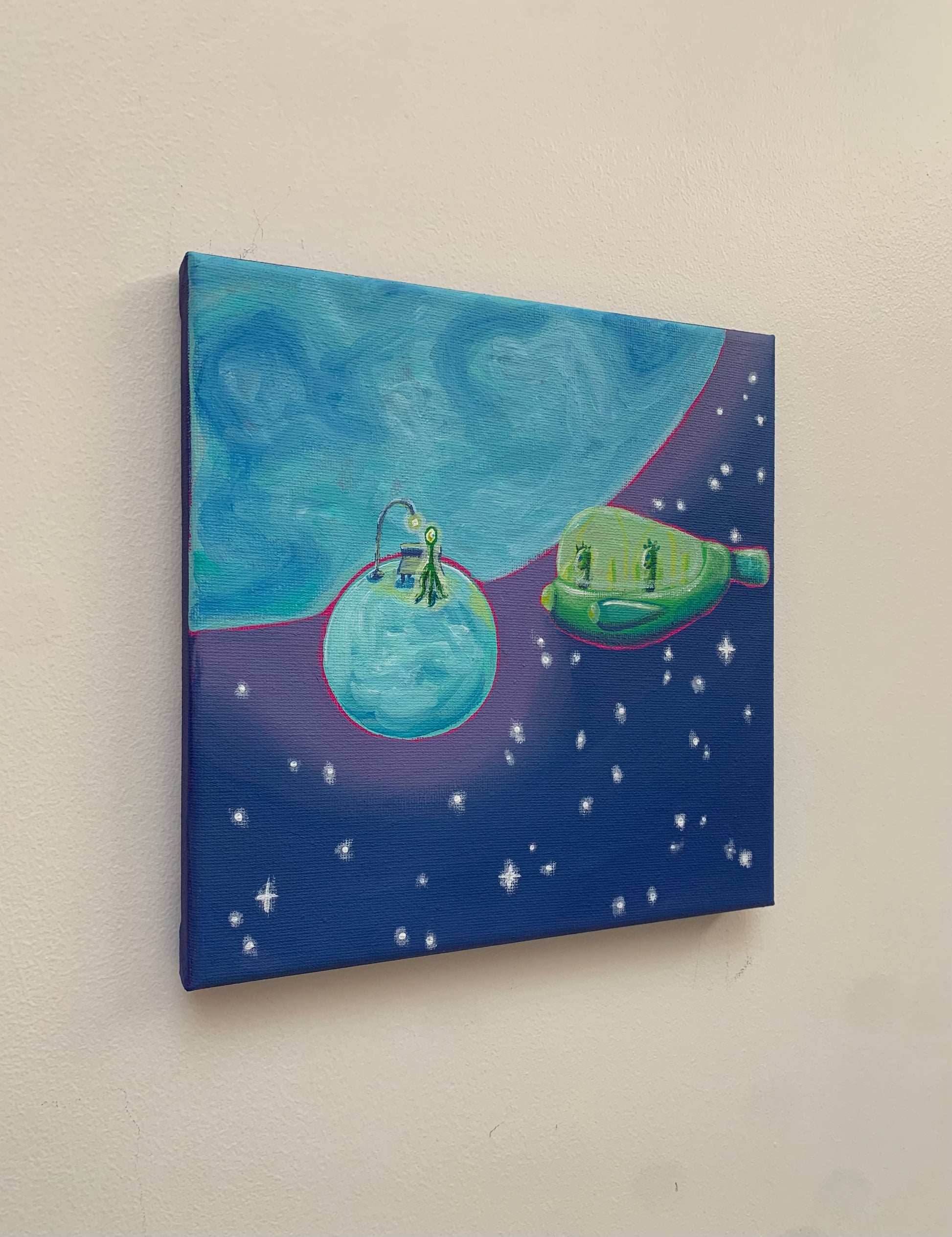 Canvas painting of a space scene with planets and stars on a beige wall.