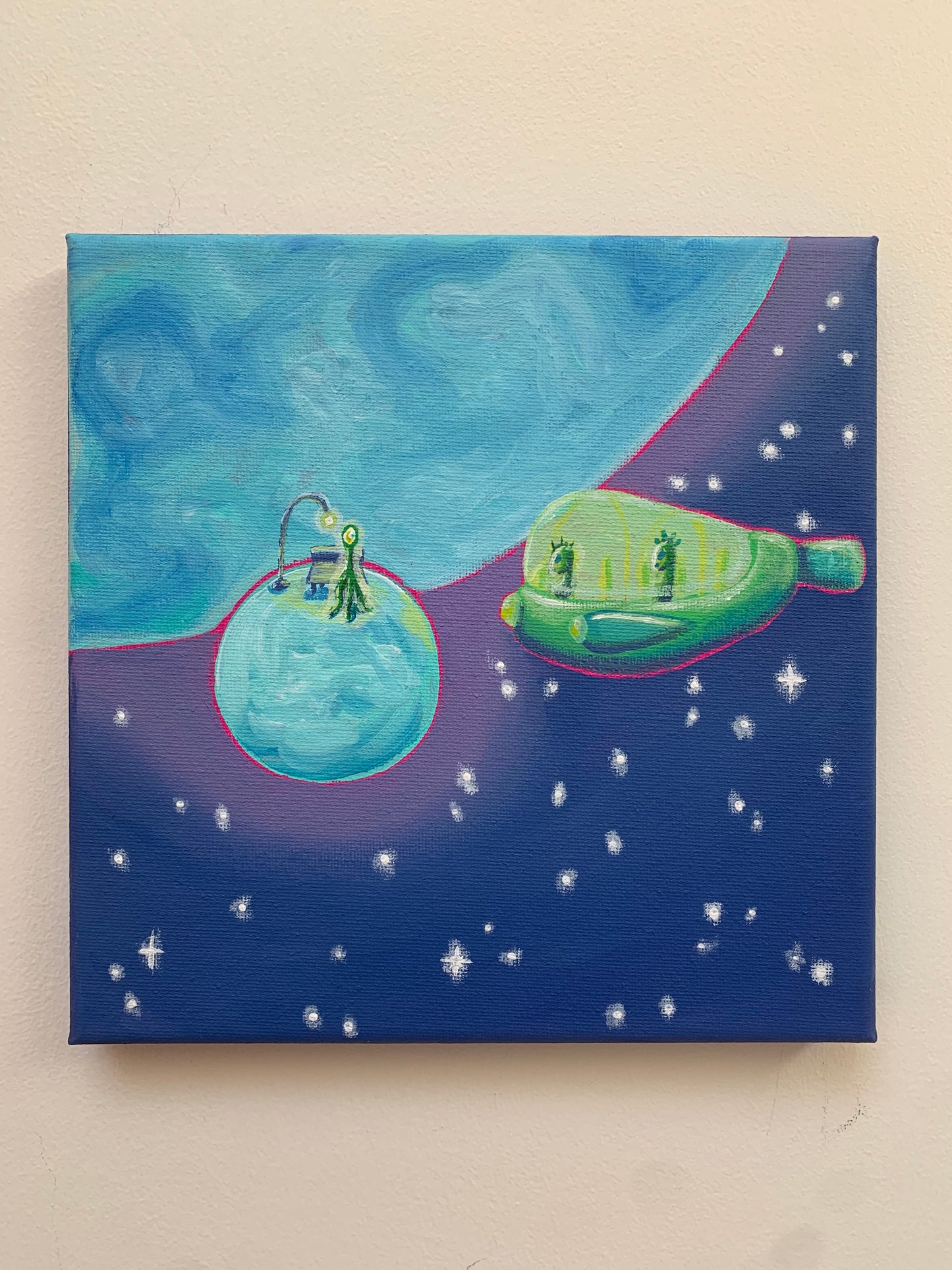 Canvas print of a space-themed artwork with planets and a green spaceship on a beige wall.