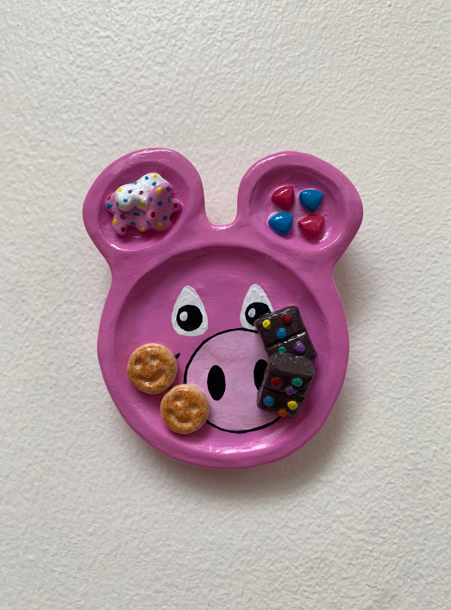 Pink animal-shaped plate with various items on a white background
