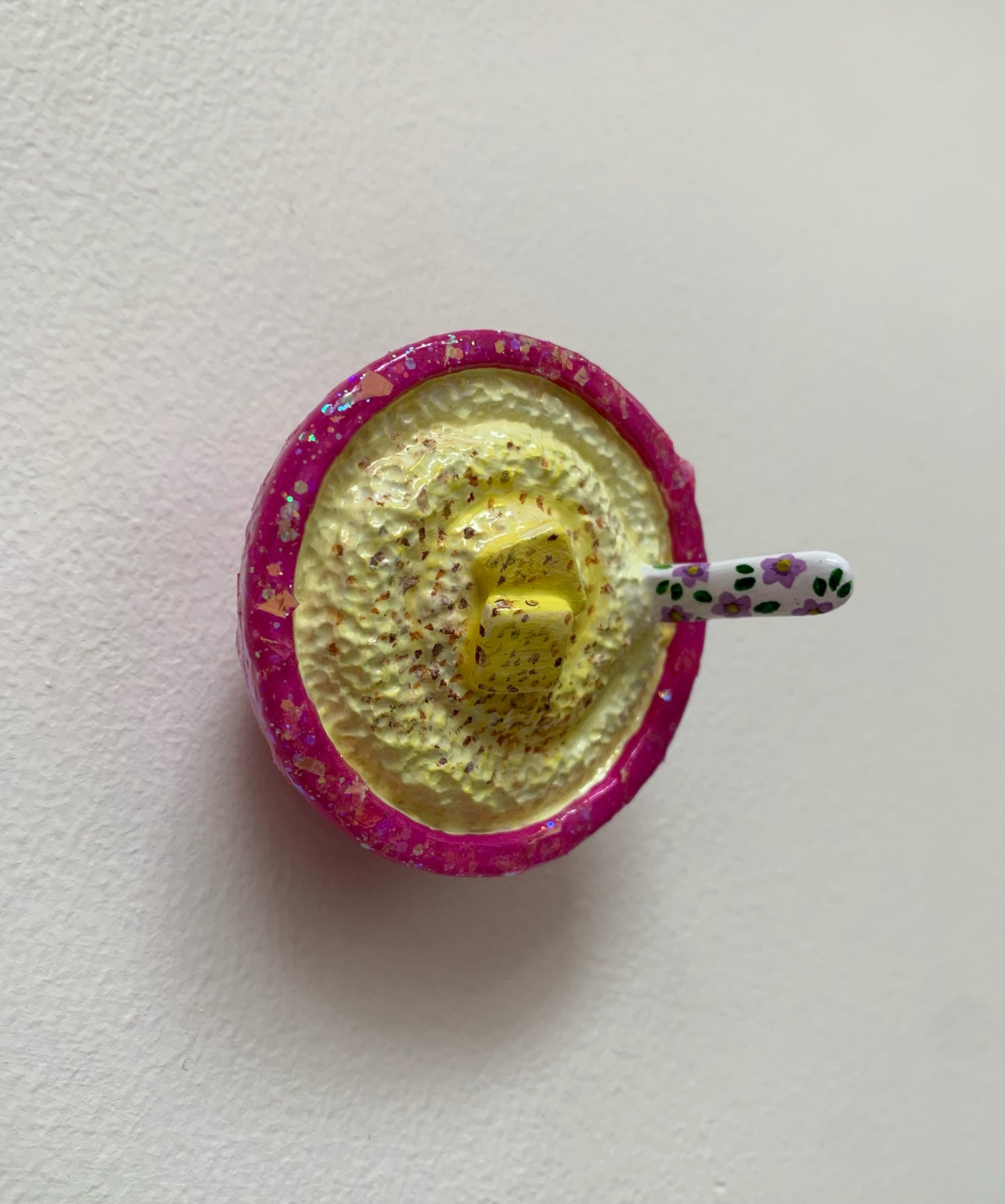 Pink glitter bowl of white and yellow grits on a white background 